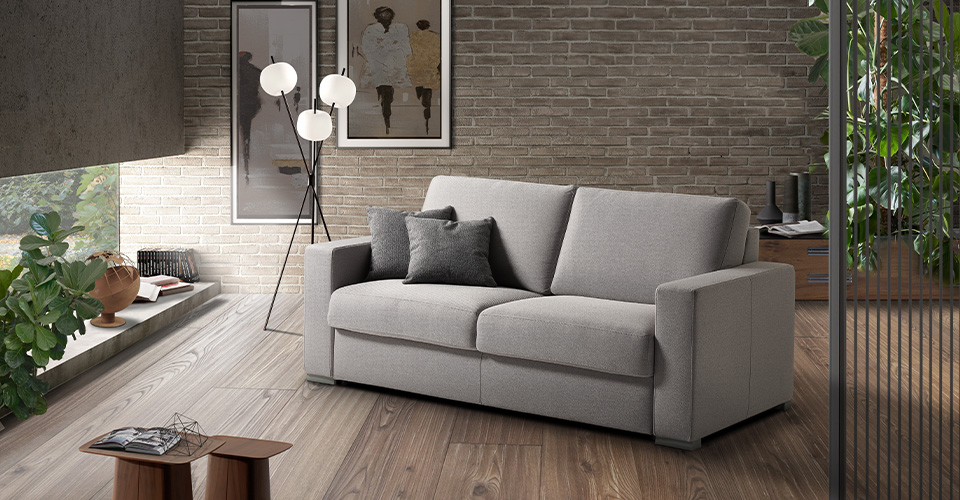 canapé convertible beige en tissu dans salon contemporain avec mur en briques et parquet bois