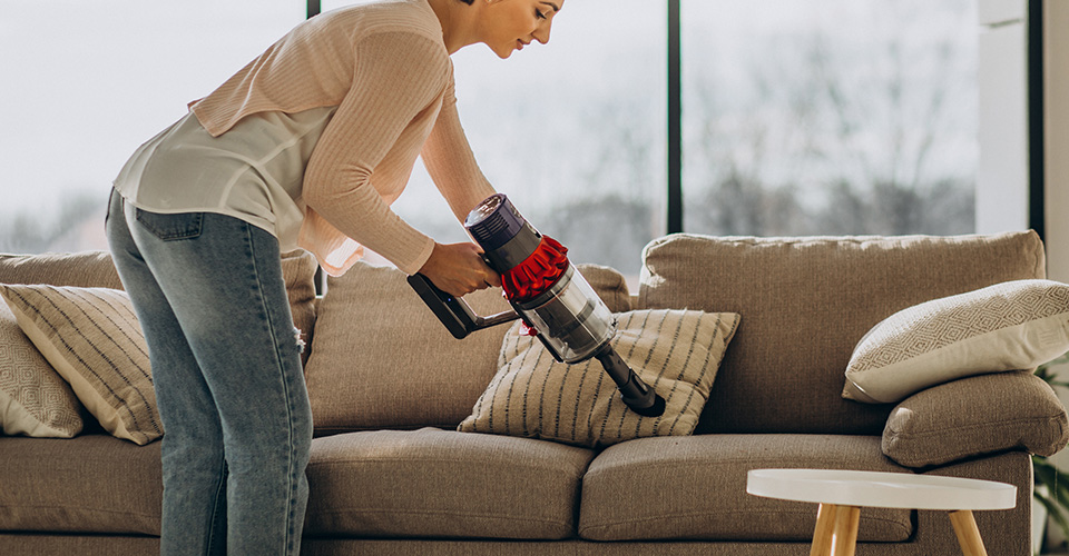 Nettoyage des recoins d'un canapé convertible avec un aspirateur à embout
