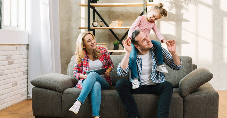 Famille installée sur un canapé convertible dans le salon d'un appartement